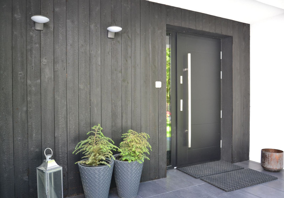 Wnękę przy głównym wejściu obłożono deskami elewacyjnymi z palonego drewna