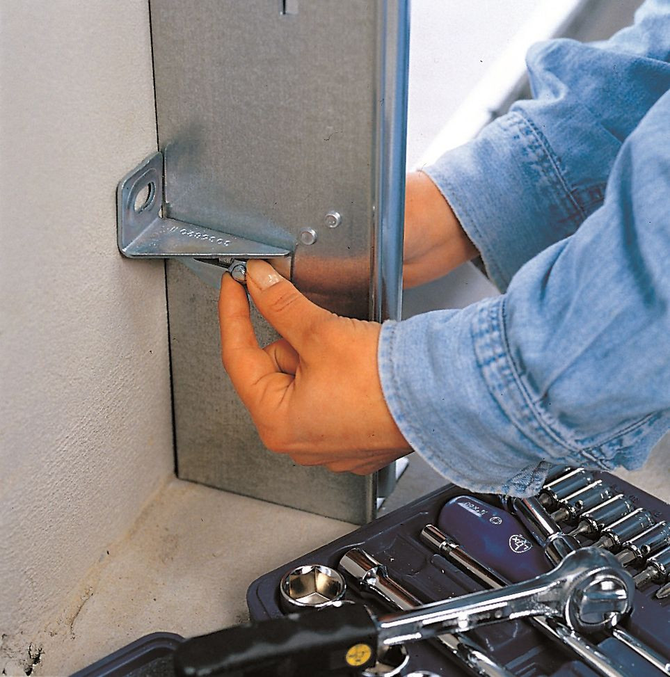 Montaż bramy segmentowej: Boczne profile ramy przymocowuje się do ściany garażu, przykręcając kątownik