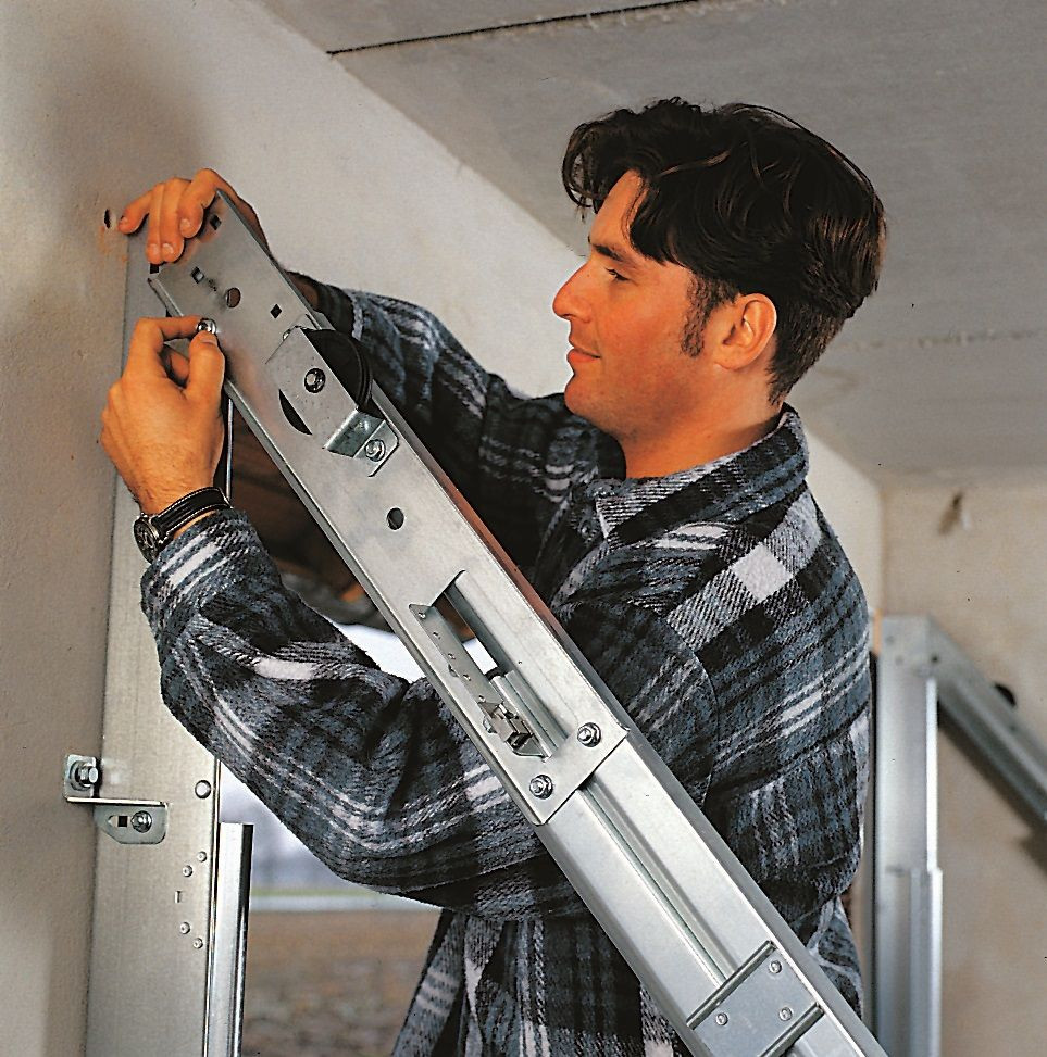 Montaż bramy segmentowej: Wstępnie zmontowane prowadnice górne osadza się w ościeżnicy i przymocowuje śrubami