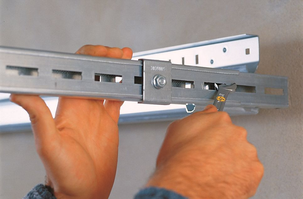 Montaż bramy segmentowej: Całą ramę (profile górne i szynę końcową) mocuje się do ścian za pomocą wysuwanego profilu