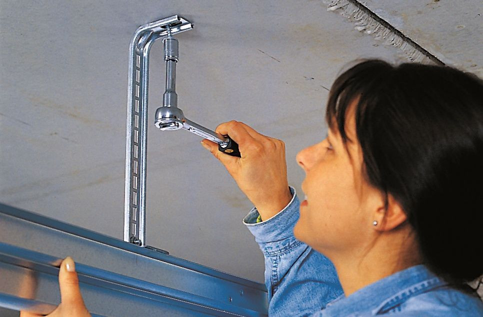 Montaż bramy segmentowej: Prowadnice podwiesza się za pomocą wcześniej zamocowanego uchwytu