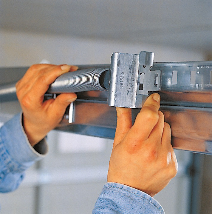 Montaż bramy segmentowej: Uruchamia się próbnie bramę i określa się odpowiedni naciąg sprężyn, który umożliwia zrównoważenie jej ciężaru