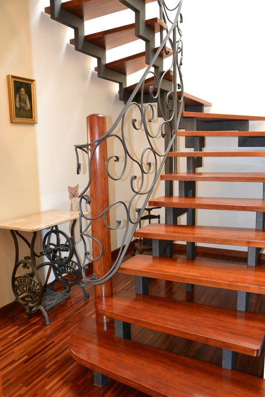 Ażurowe zabiegowe schody dodają przestronności wąskiemu korytarzowi na parterze