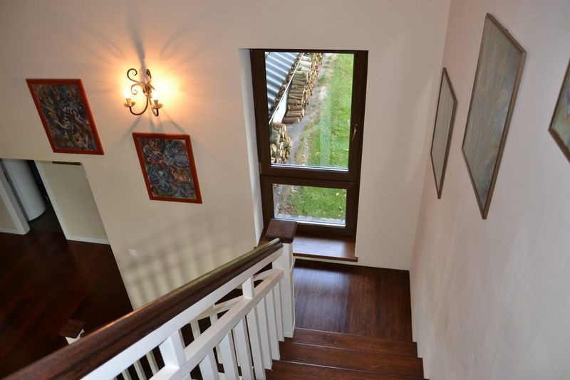 Klatka schodowa z białą drewnianą balustradą i stopnicami w naturalnym kolorze drewna