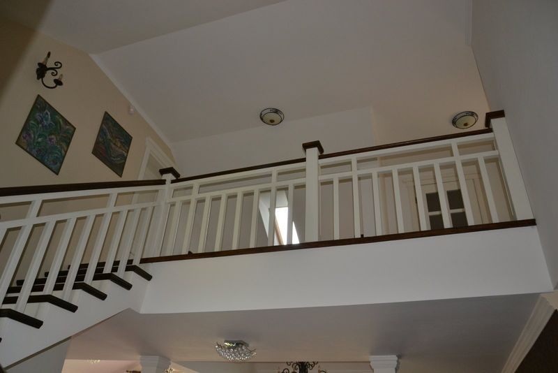 Klatka schodowa z białą drewnianą balustradą i stopnicami w naturalnym kolorze drewna