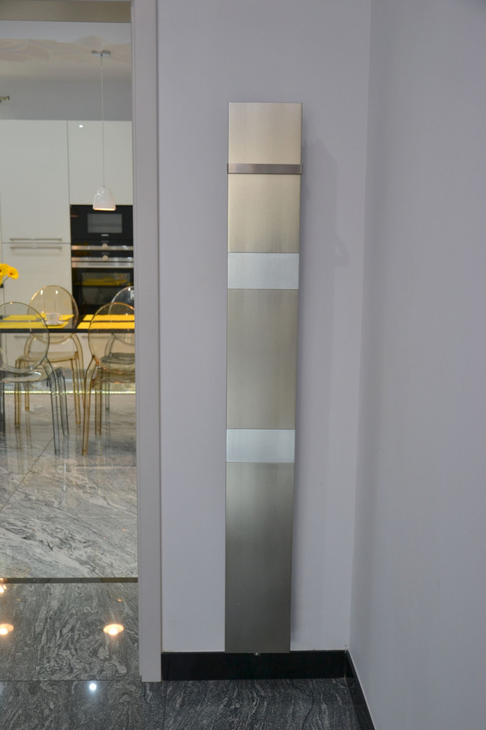 Ozdobny grzejnik ulokowano między salonem a kuchnią