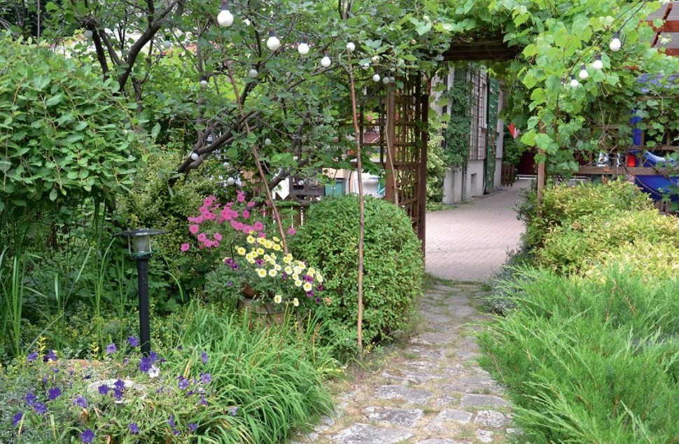 Między wybrukowanym kostką dziedzińcem i altaną właściciele poprowadzili ścieżkę z piaskowca. Obrzeża wykonali z kostki granitowej