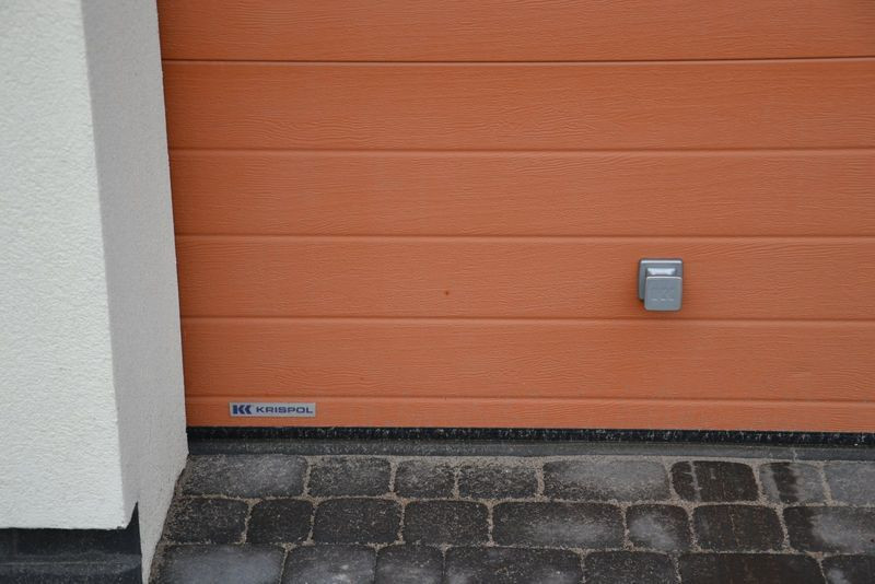 Właściciele dodatkowo wyposażyli bramę w pochwyt, ręczny rygiel oraz przycisk na ścianie garażu (przy wewnętrznym ciągu komunikacyjnym)