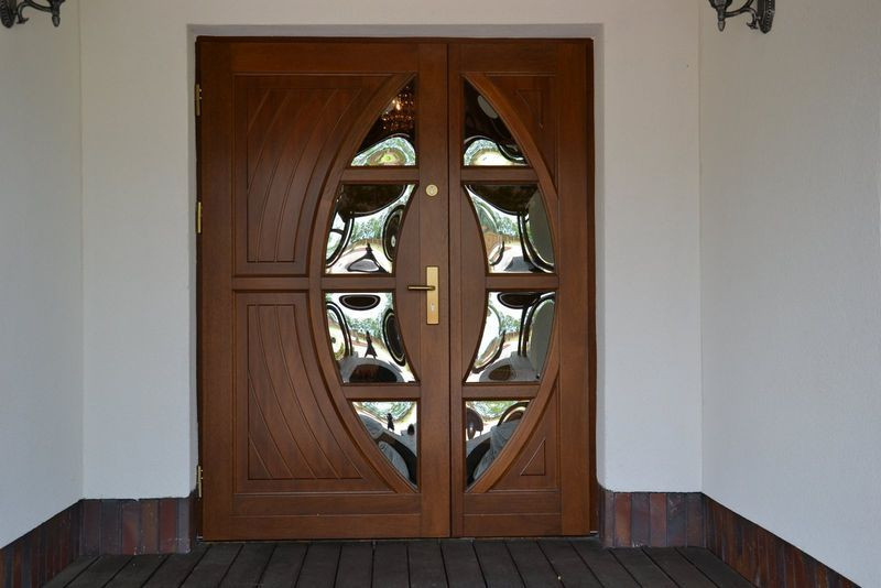 Drzwi z drewna meranti oszklono dmuchanym szkłem, zachowującym się jak lustro weneckie. Mają solidne zawiasy i zamki