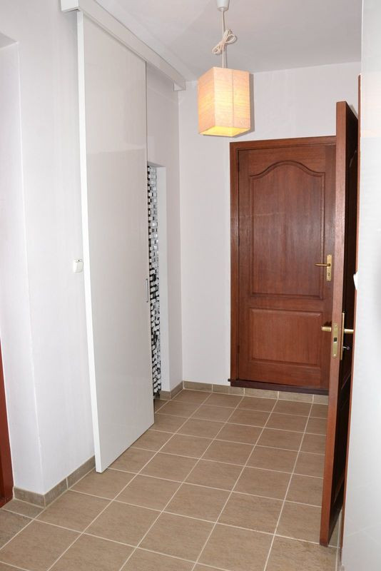 Pełne drzwi do łazienki i pokoju gościnnego. Białe lakierowane drzwi przesuwne do garderoby