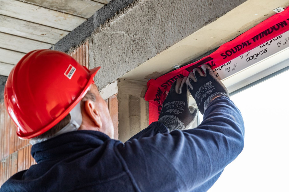 Przyklejanie taśmy okiennej od wewnątrz pomieszczenia w systemie SWS. fot. Soudal