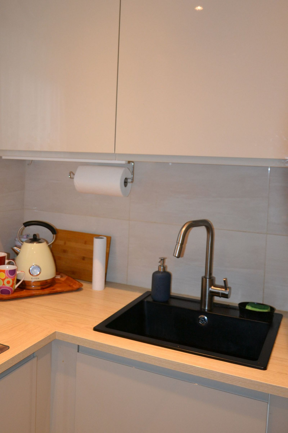 Elementy zabudowy otwiera się na dotyk, widoczny sprzęt (m.in. zlewozmywak) ma kolor czarny