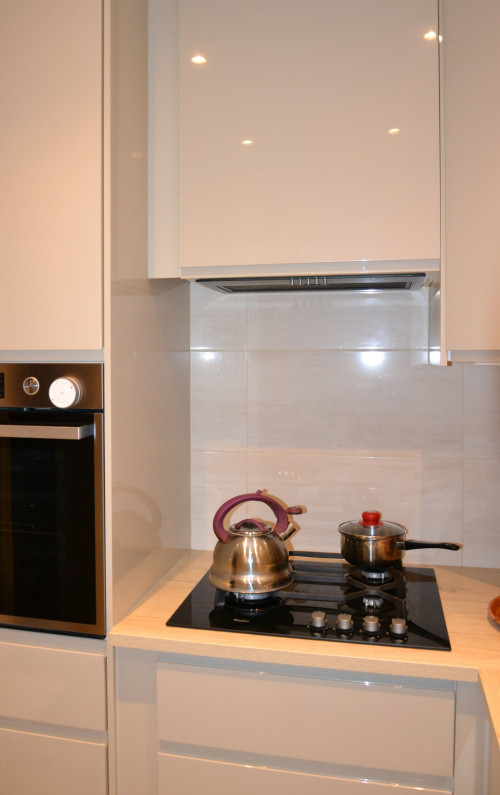 W laminowanym blacie szerokości 60 cm oprawiono płytę gazową, nad nią (w wiszącej szafce) - okap