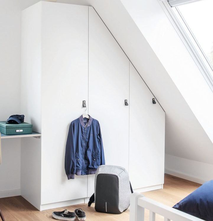 Biała szafa dopasowana do skosów na poddaszu