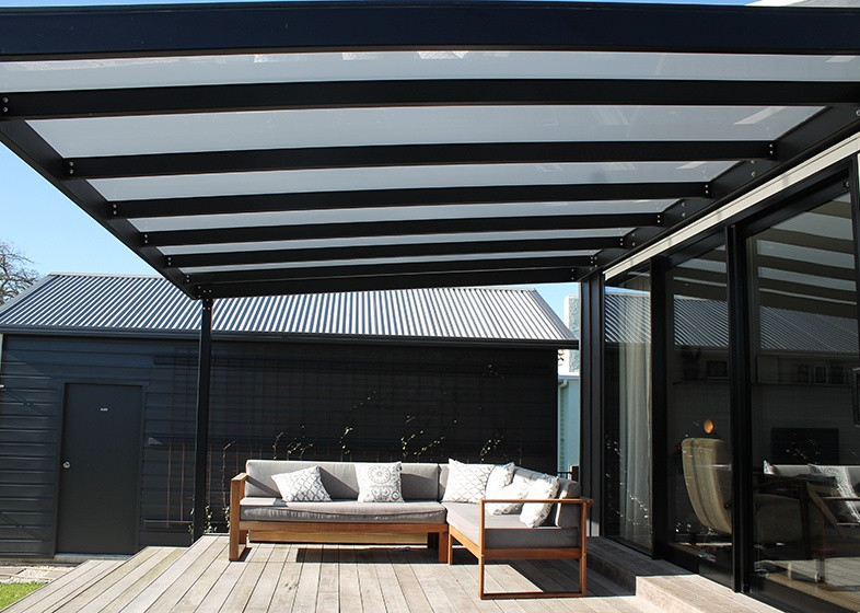Zadaszenie tarasu za domem z grafitowcyh płyt poliwęglanowych. Efekt w słoneczny dzień