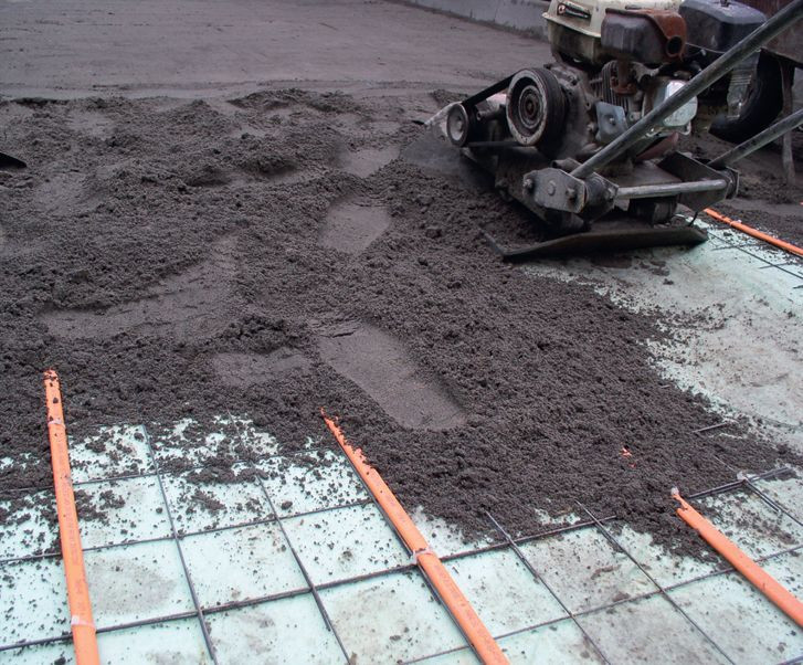 Układanie instalacji przeciwoblodzeniowej na podjeździe. Pod płyty betonowe lub kostkę kable układa się w warstwie podsypki