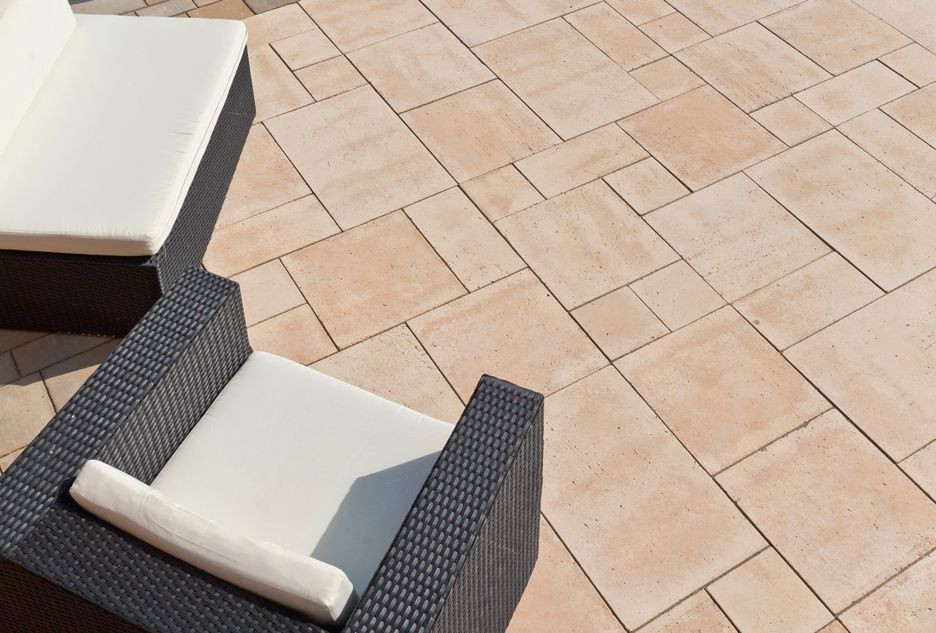 Tarasy z kostki lub płyt w ciepłym beżowym kolorze dobrze komponują się z ogrodową zielenią