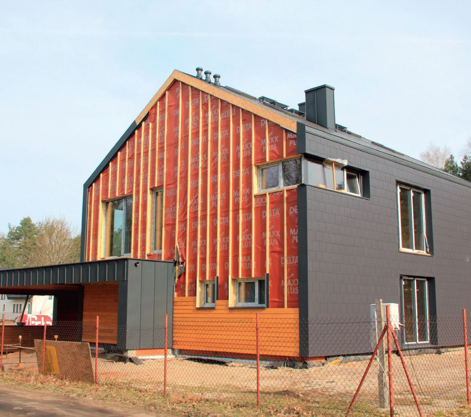 Różne elewacje na różnych ścianach - drewniana oblicówka i płytka włókno-cementowa, schodząca z dachu na mur