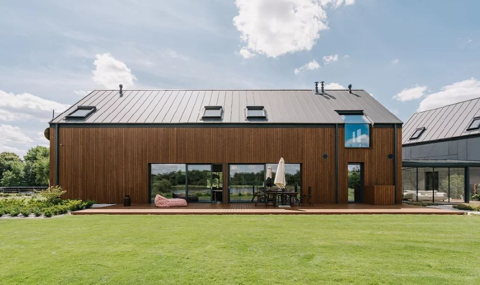 Elewację domu zdobią gładkie deski z termososny o karmelowym odcieniu.