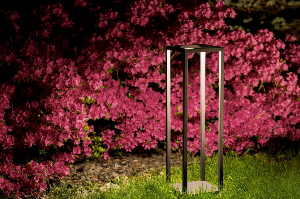 Lampa stojąca do ogrodu SYMMETRY LED świeci się górnymi krawędziami korpusu.