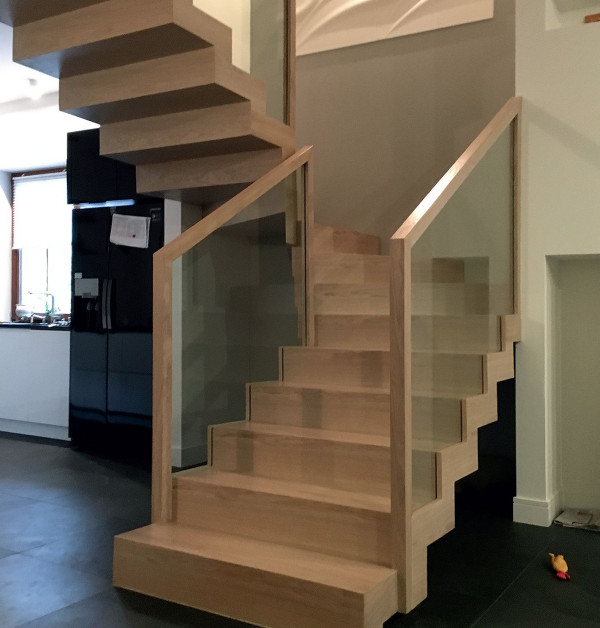 Schody dywanowe ze szklaną balustradą i drewnianą poręczą