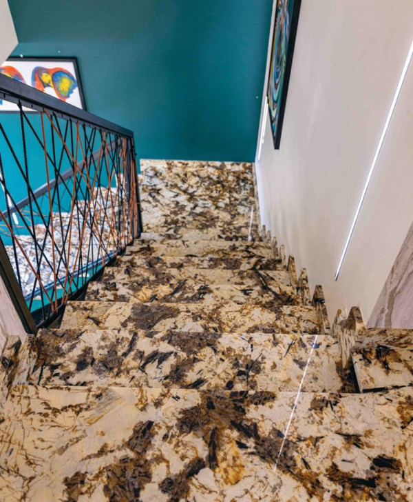 Schody dwubiegowe ze spocznikiem. Konstrukcja żelbetowa. Stopnie i podstopnice wykończone kamieniem w odcieniach brązu