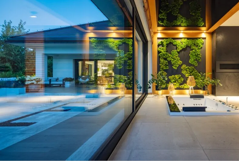 Dzięki przeszkleniom umieszczonym na dwóch sąsiadujących ścianach narożnych można podziwiać pięknie zaaranżowany ogród.