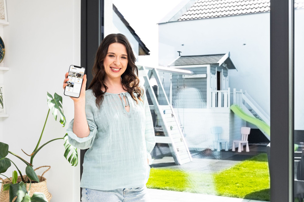 Kobieta trzyma smartfon z aplikacją do sterowania inteligentnym domem